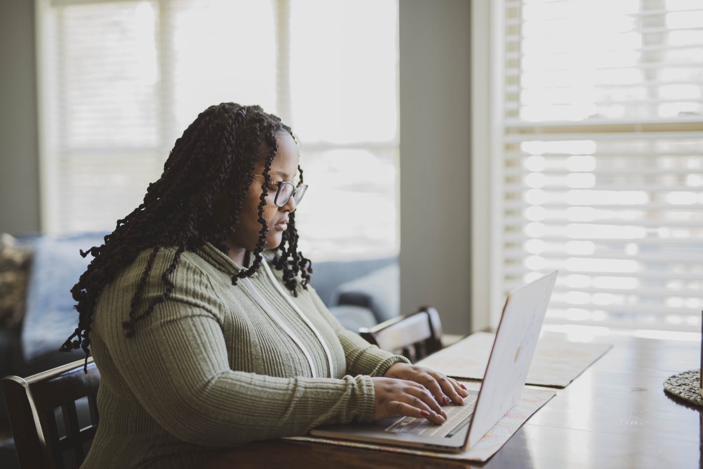 An engineer writing code at her laptop by a window